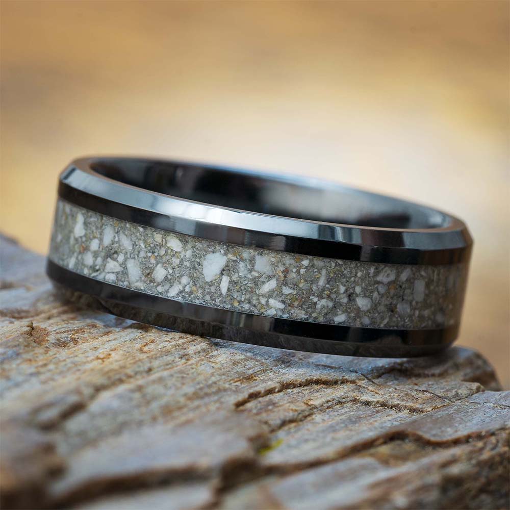 A dark ring with ash inlay on a wooden surface.