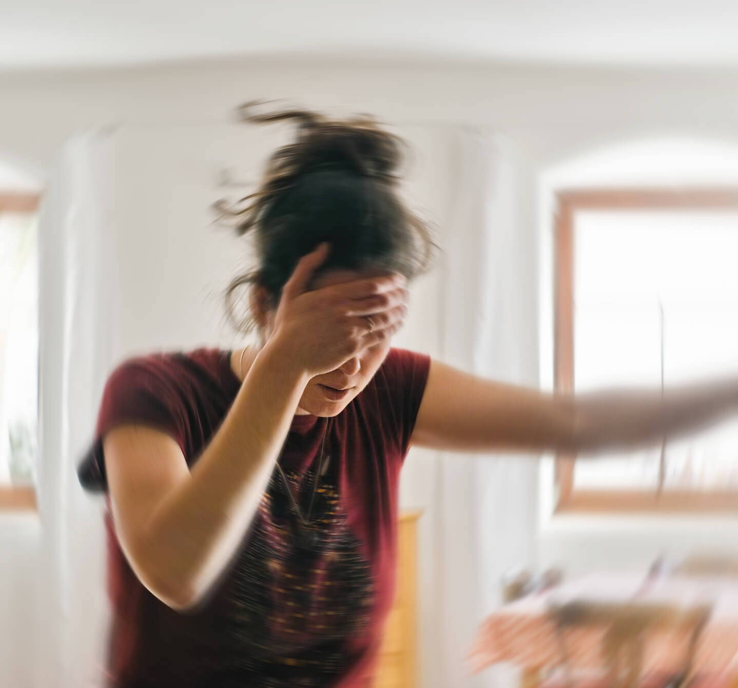 En kvinne holder en hånd opp mot pannen mens hun støtter seg til en vegg, det kan se ut som hun er plaget av hodepine. Kan det være allergi?