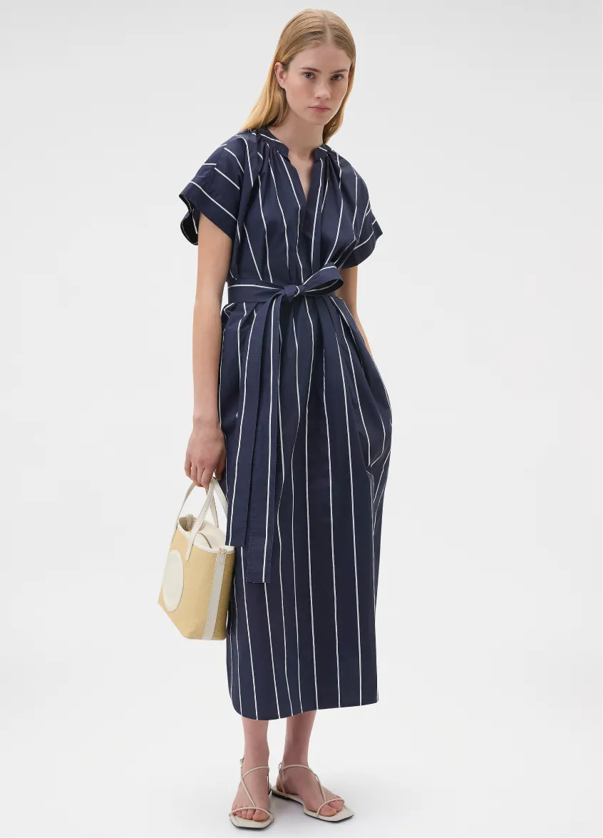Woman in a striped dress holding a yellow bag.
