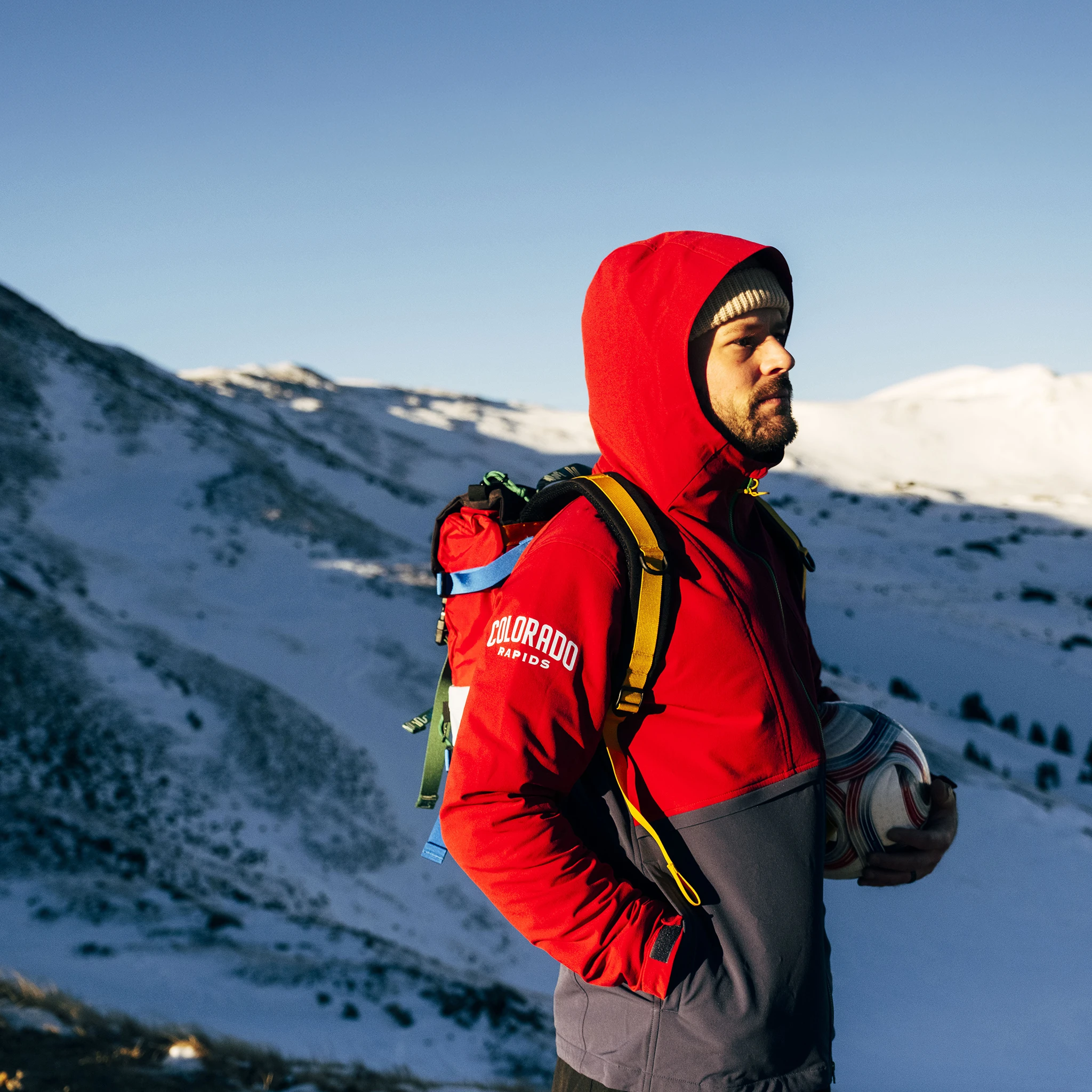 Person in winter gear standing on snowy mountain landscape.