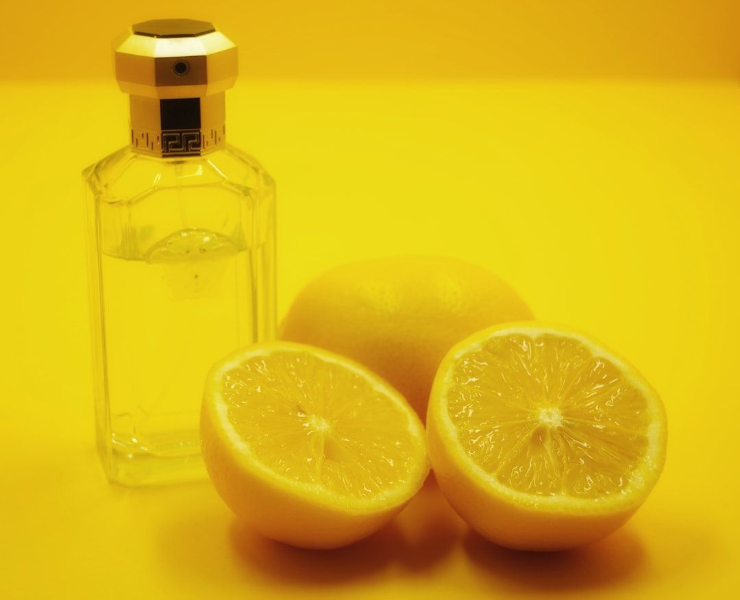 two lemons and a bottle of alcohol on a yellow background