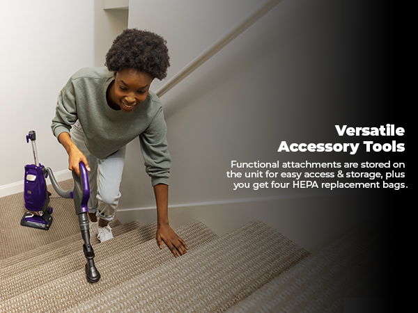 Person vacuuming stairs with a purple vacuum cleaner and accessory tools.