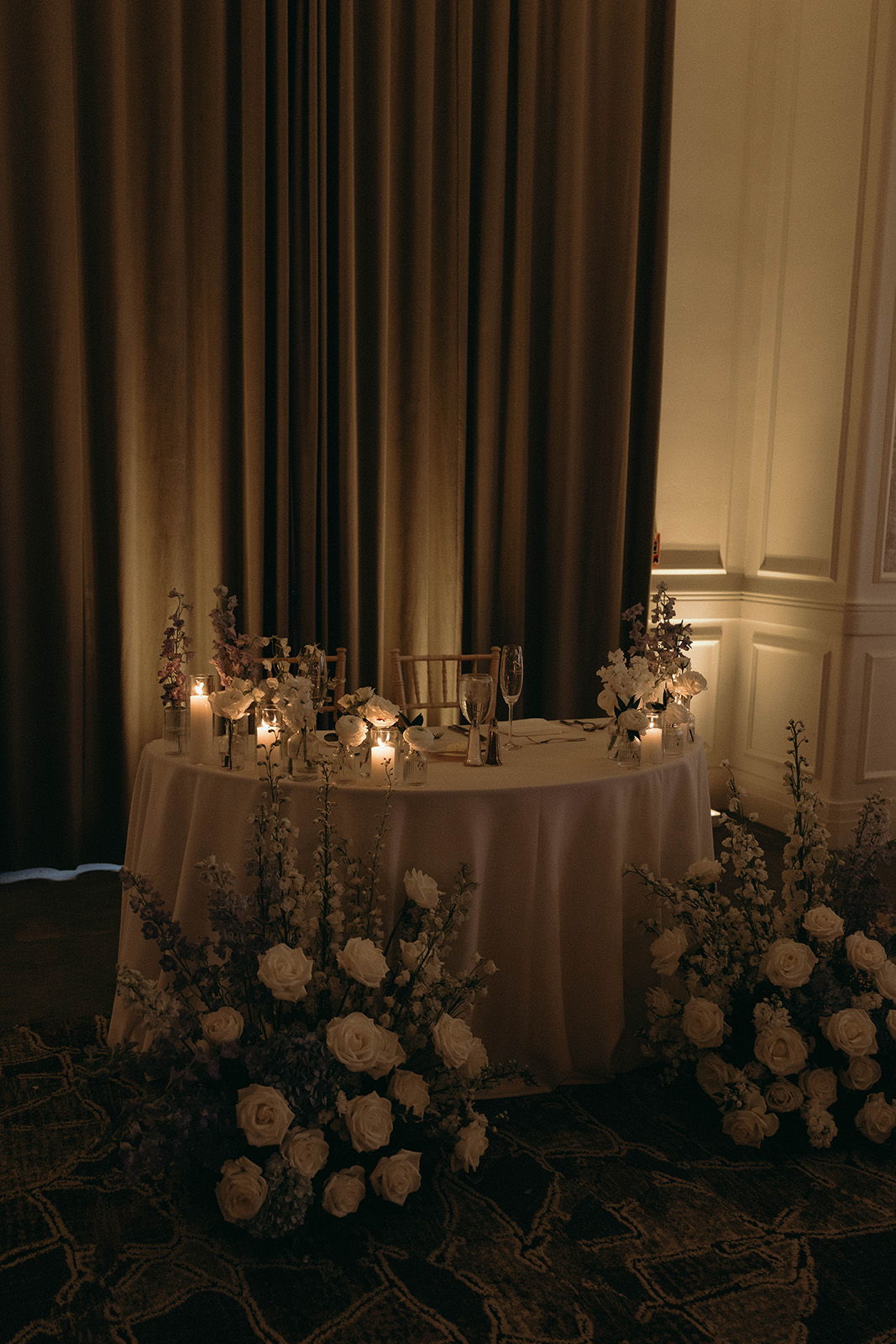 Elegant table with candles and floral arrangements, set against a curtain backdrop.