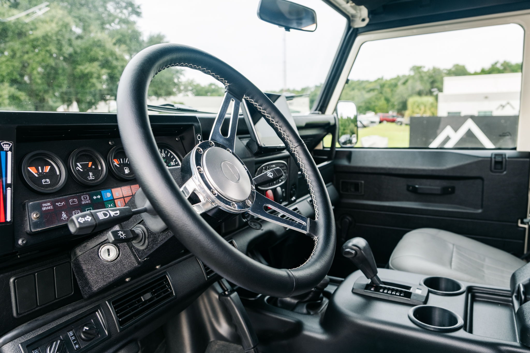 Interior view of a vehicle showing the steering wheel and dashboard controls.
