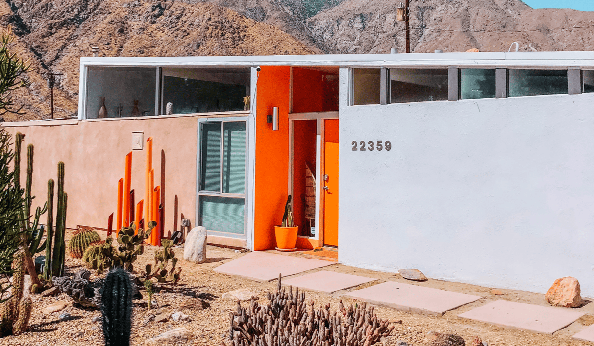 The Dazey Desert House features midcentury modern lines and bright orange color palette against the backdrop of desert mountains.