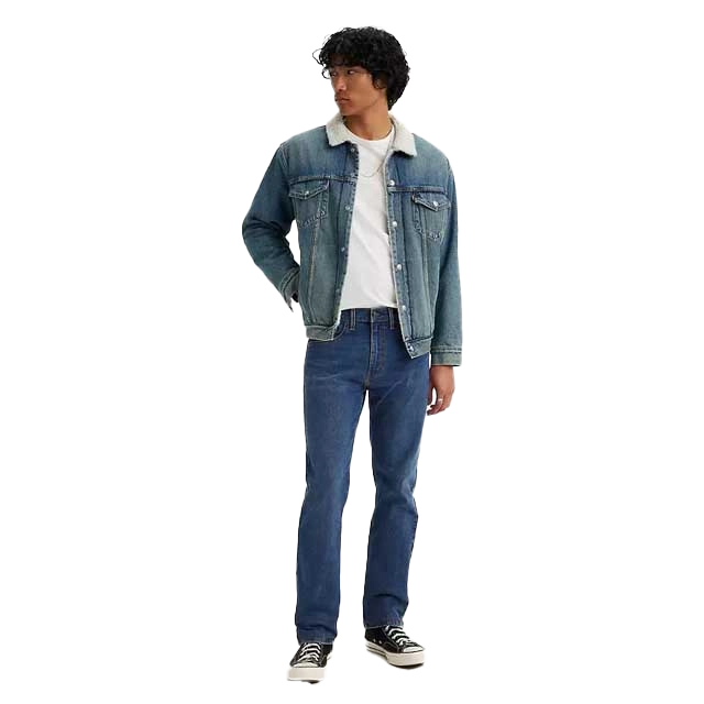 Person wearing a denim jacket, white shirt, and jeans, standing casually.