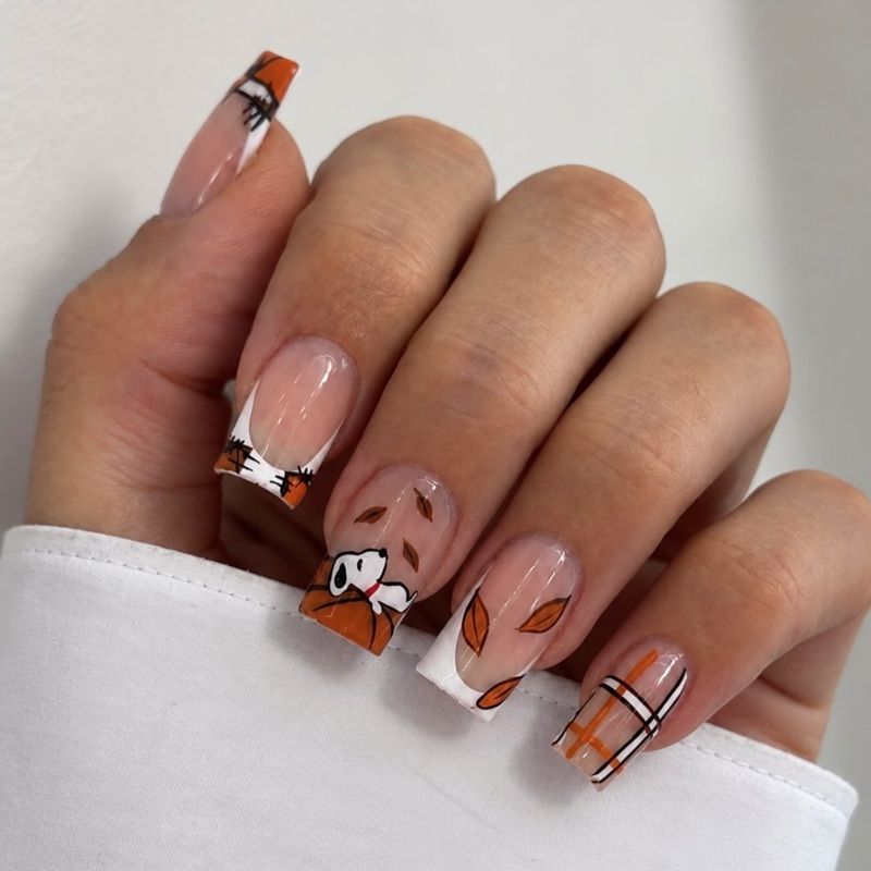 Nails with orange and white designs, featuring leaves and abstract patterns.