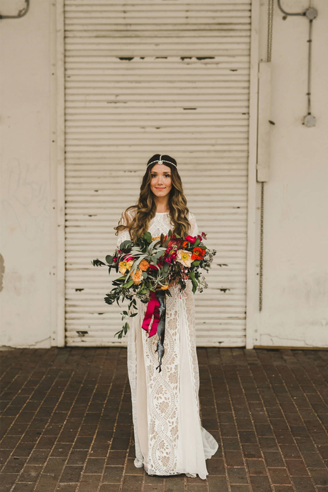 Grace Loves Lace bride wearing Inca wedding dress with floral arrangement