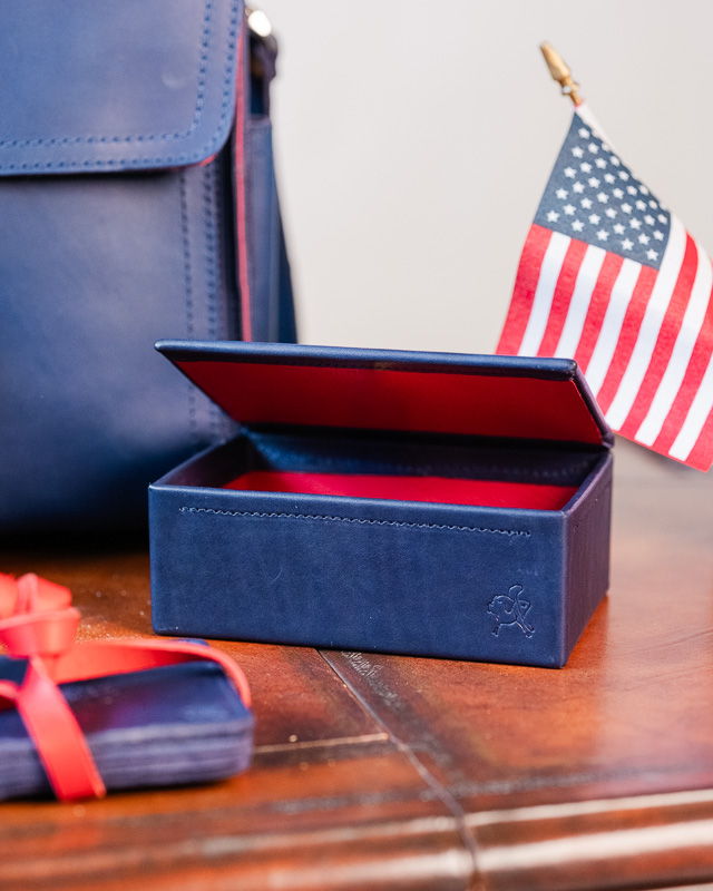 A navy box with a red interior, American flag, and leather bag.
