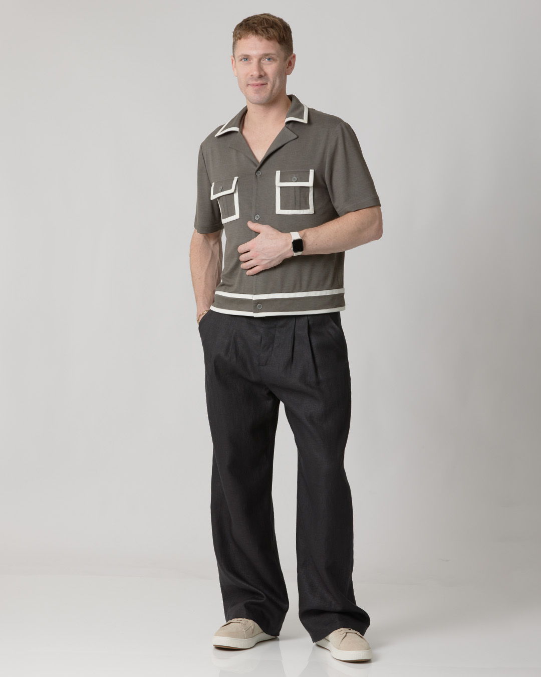 Man in stylish outfit standing against a neutral background.
