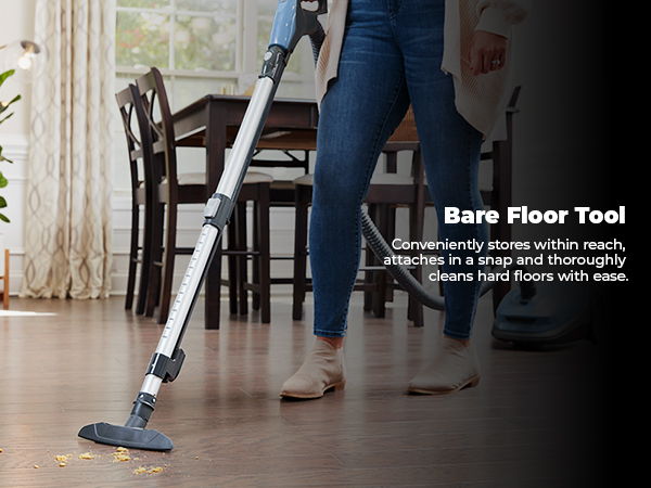 Person using a vacuum cleaner's bare floor tool on hardwood floors.