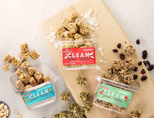 Three containers of granola snacks on a wooden cutting board.