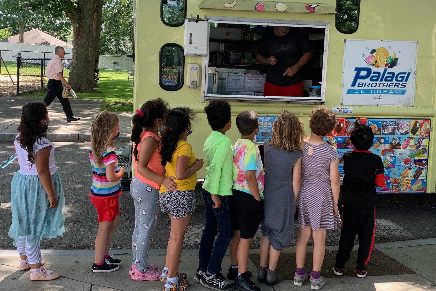 Local children line up to get free treats from an ice cream truck, courtesy of the Aramli Foundation
