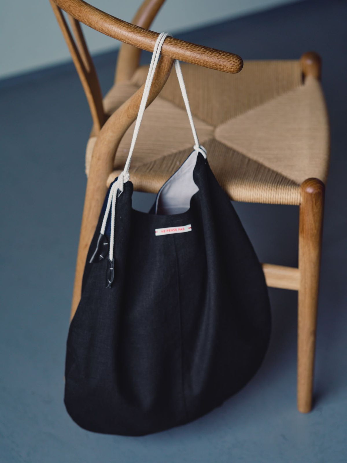 A black bag hanging from a wooden chair.