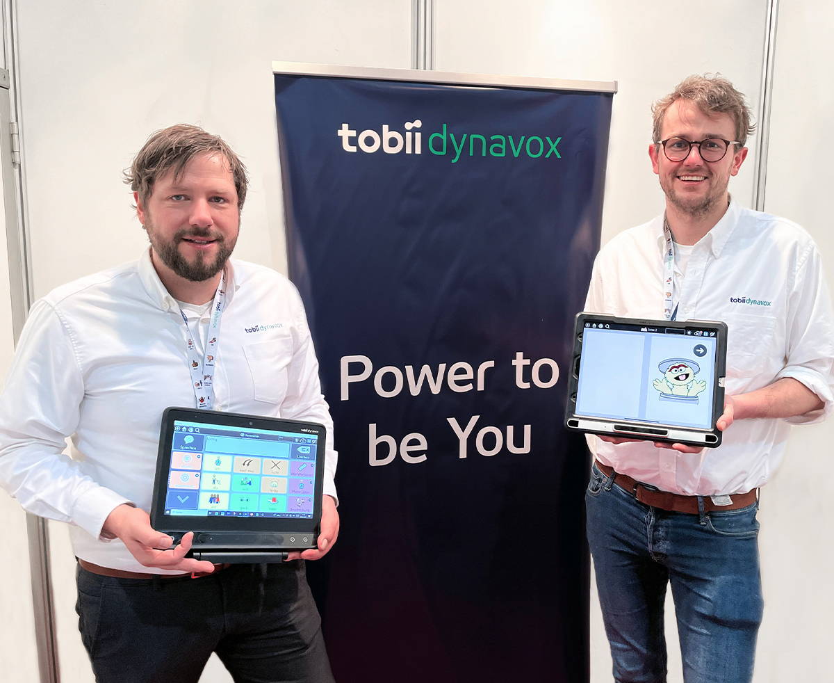 Zwei Tobii Dynavox Kollegen bei einer Veranstaltung mit den beiden Kommunikationsgeräten TD Pilot und TD I-Serie. 