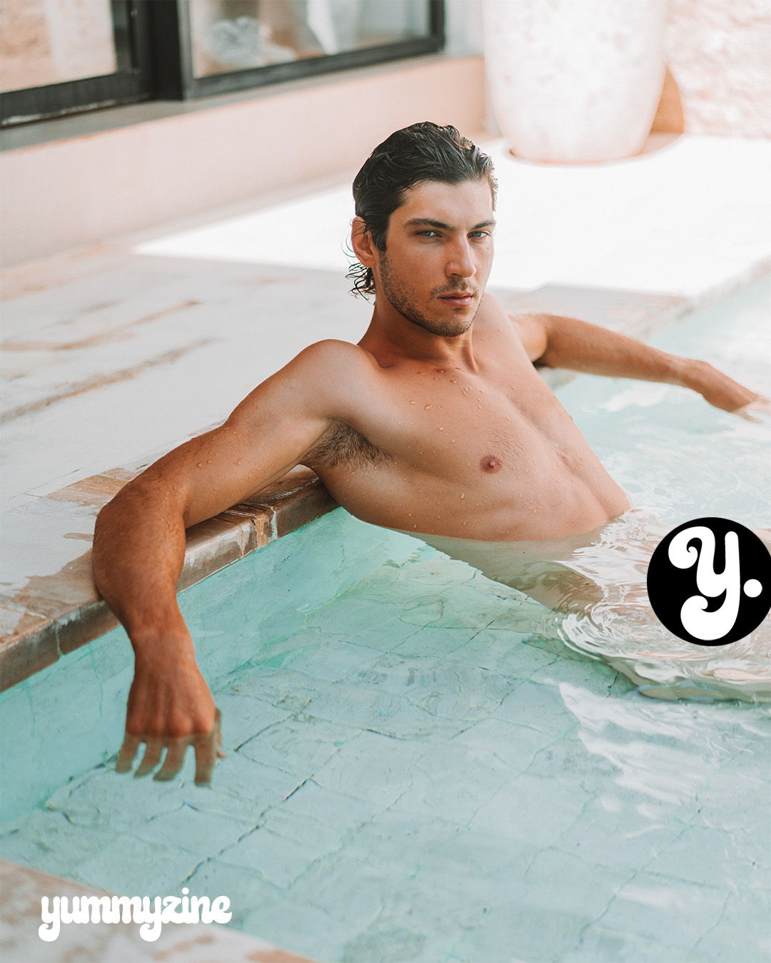 A shirtless man relaxing in a pool.