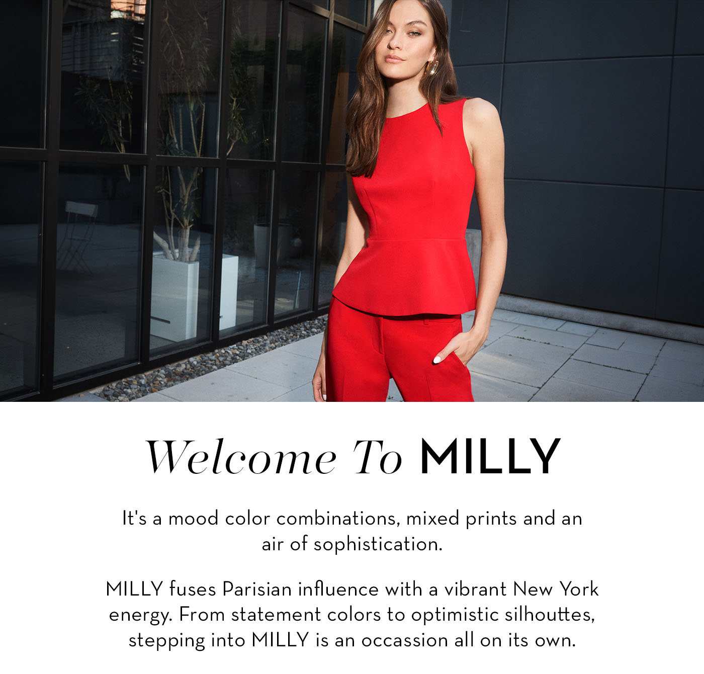 A woman in a red outfit stands confidently against a modern building backdrop.