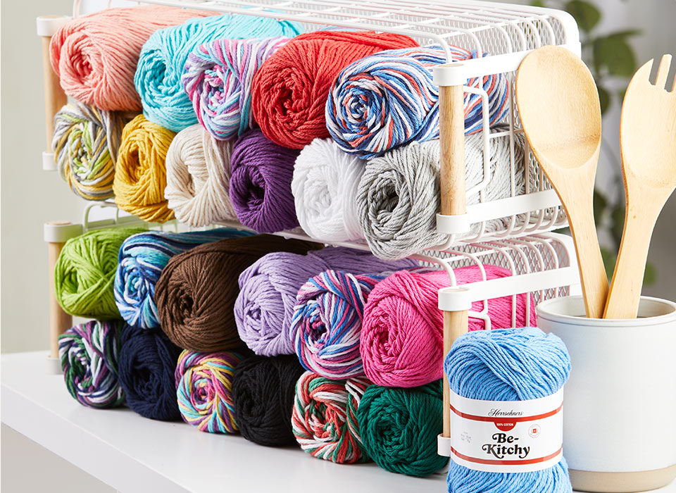 Colorful Herrschners Be-Kitchy yarn skeins neatly arranged in a storage container.