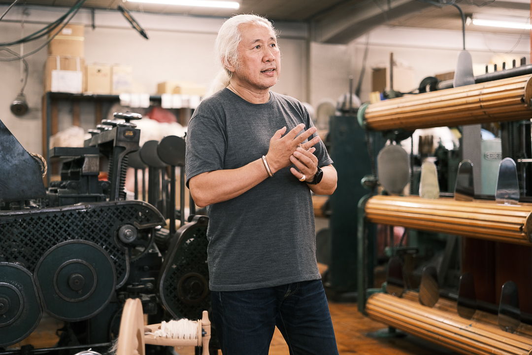 Person speaking in a workshop surrounded by machinery and equipment.