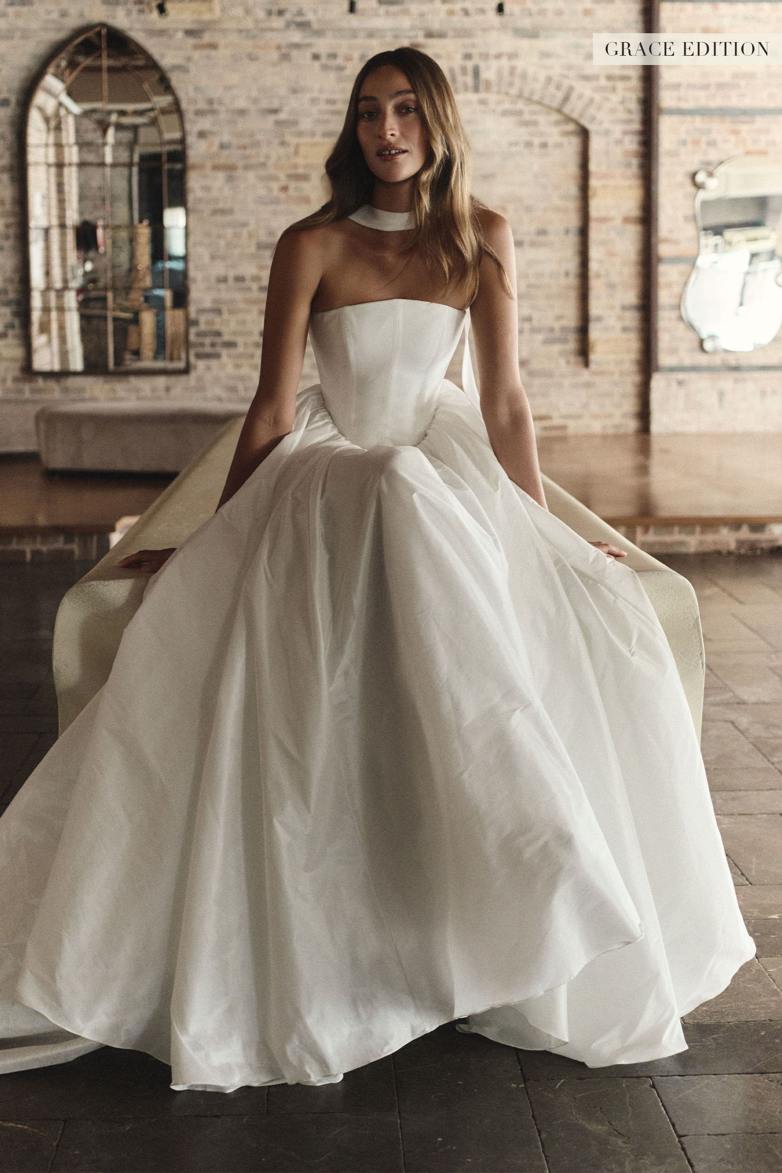 A woman wearing a strapless white ball gown wedding dress with a structured bodice and full skirt