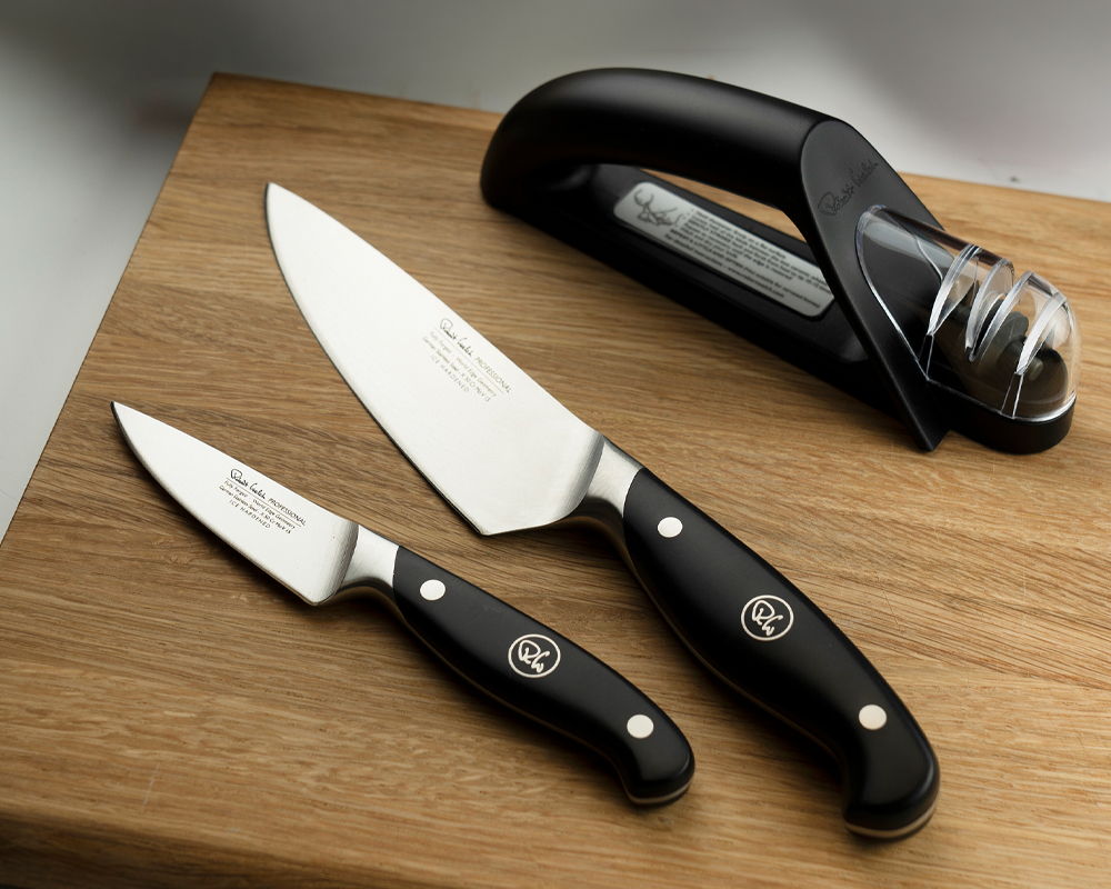 Two Professional Kitchen Knives and the Robert Welch Hand-held Knife Sharpener on the Oak Classic Chopping Board