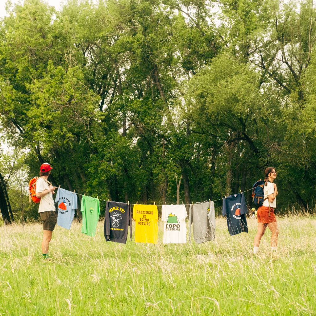 Two people walking in a field with clothes hanging on a line.
