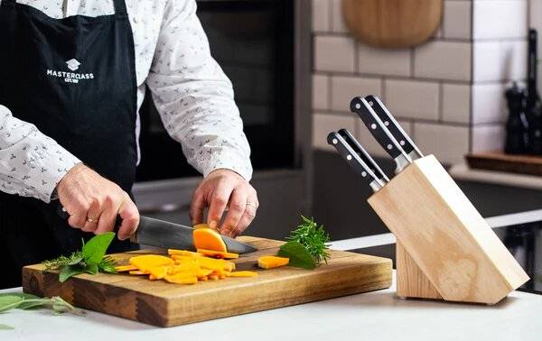 Someone slicing a vegetable with a knife on a chopping board.