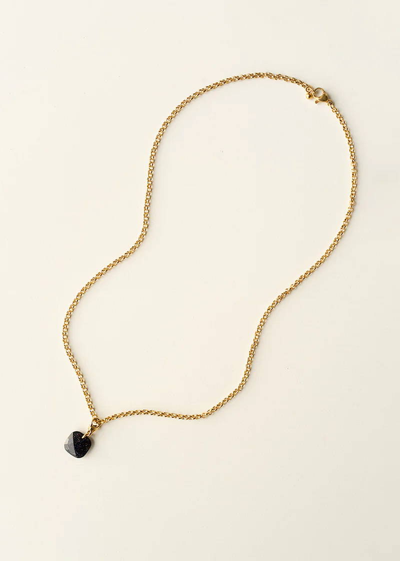 A gold chain necklace with a black faceted square pendant