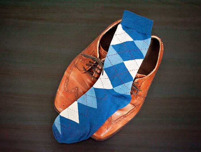 Dusty blue men's argyle dress socks displayed on a pair of brown oxfords