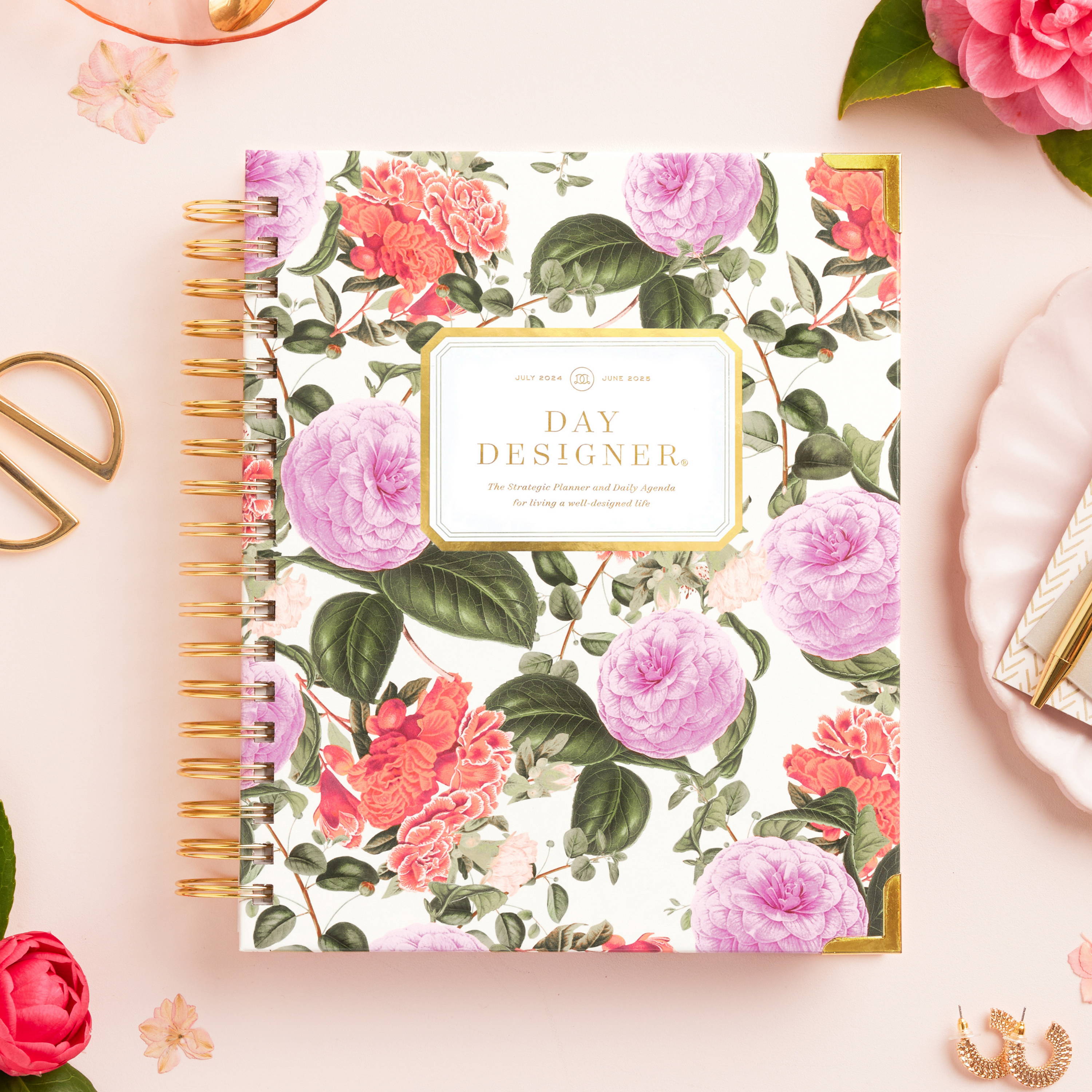 pretty pink floral closed planner on beige background, with gold scissors, dried pink flowers, dish and earings