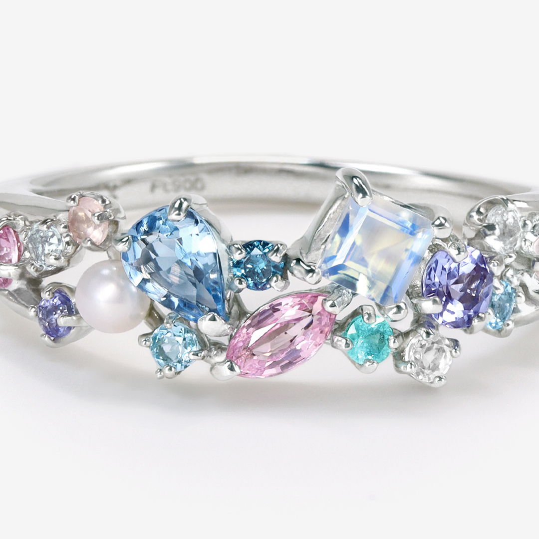 A decorative ring featuring various colorful gemstones and a pearl.