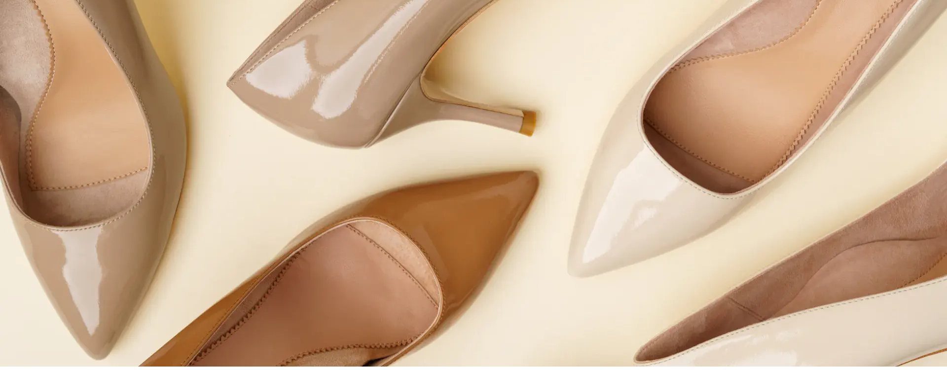 A collection of stylish high-heeled shoes in various neutral colors.