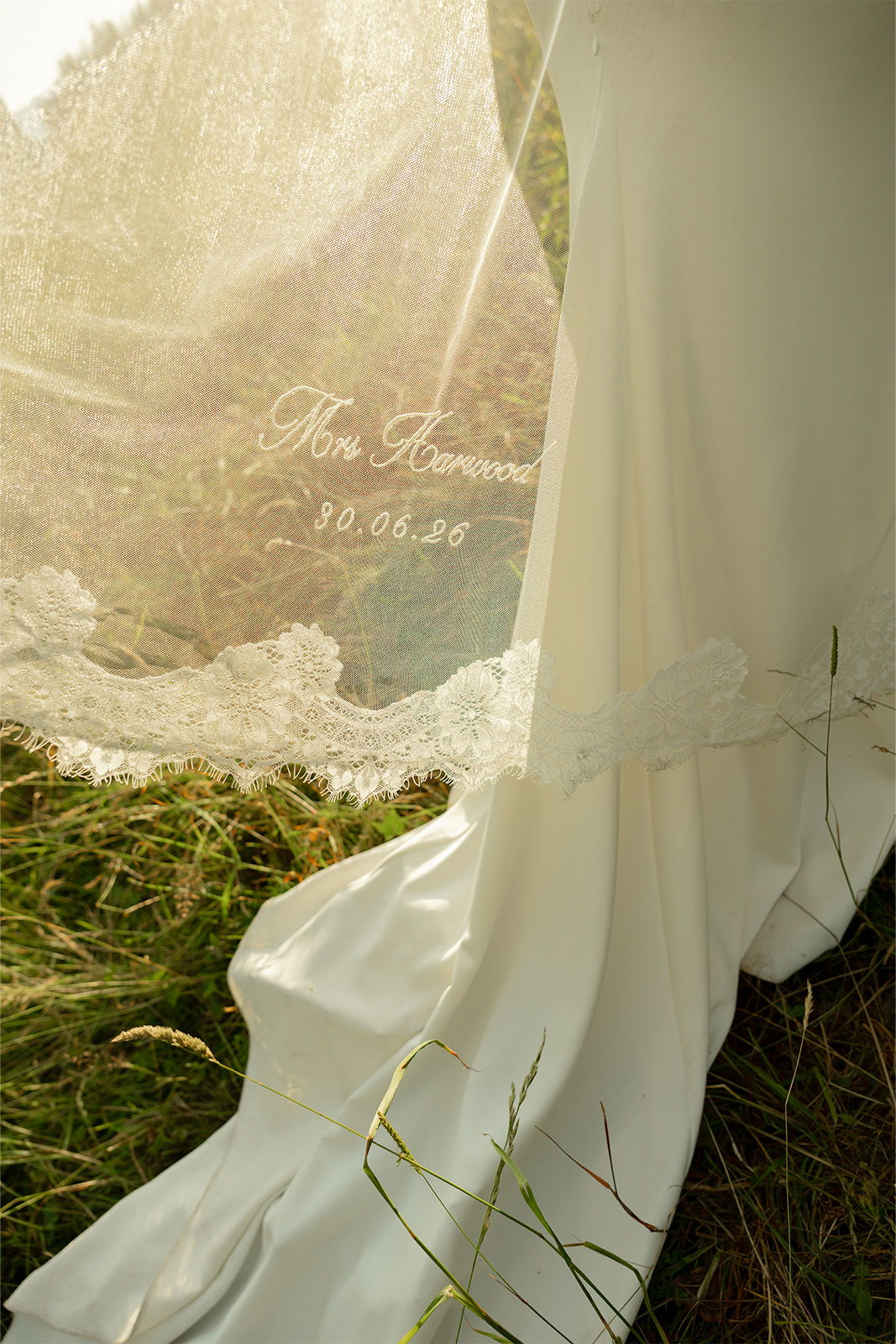 Bridal gown and veil in a grassy setting with decorative lace.