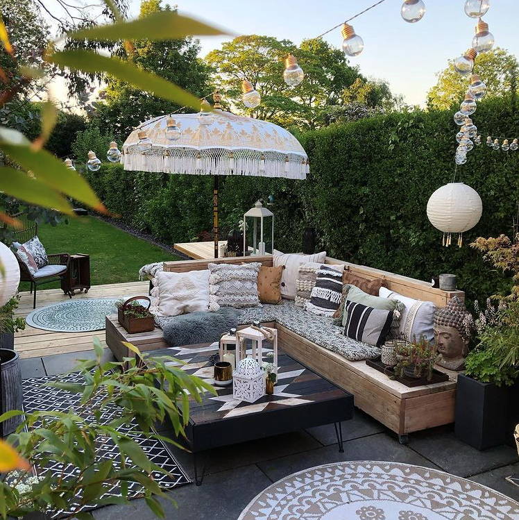Outdoor seating space with festoons hung high and Lucena lanterns displayed with garden lanterns sat on table 