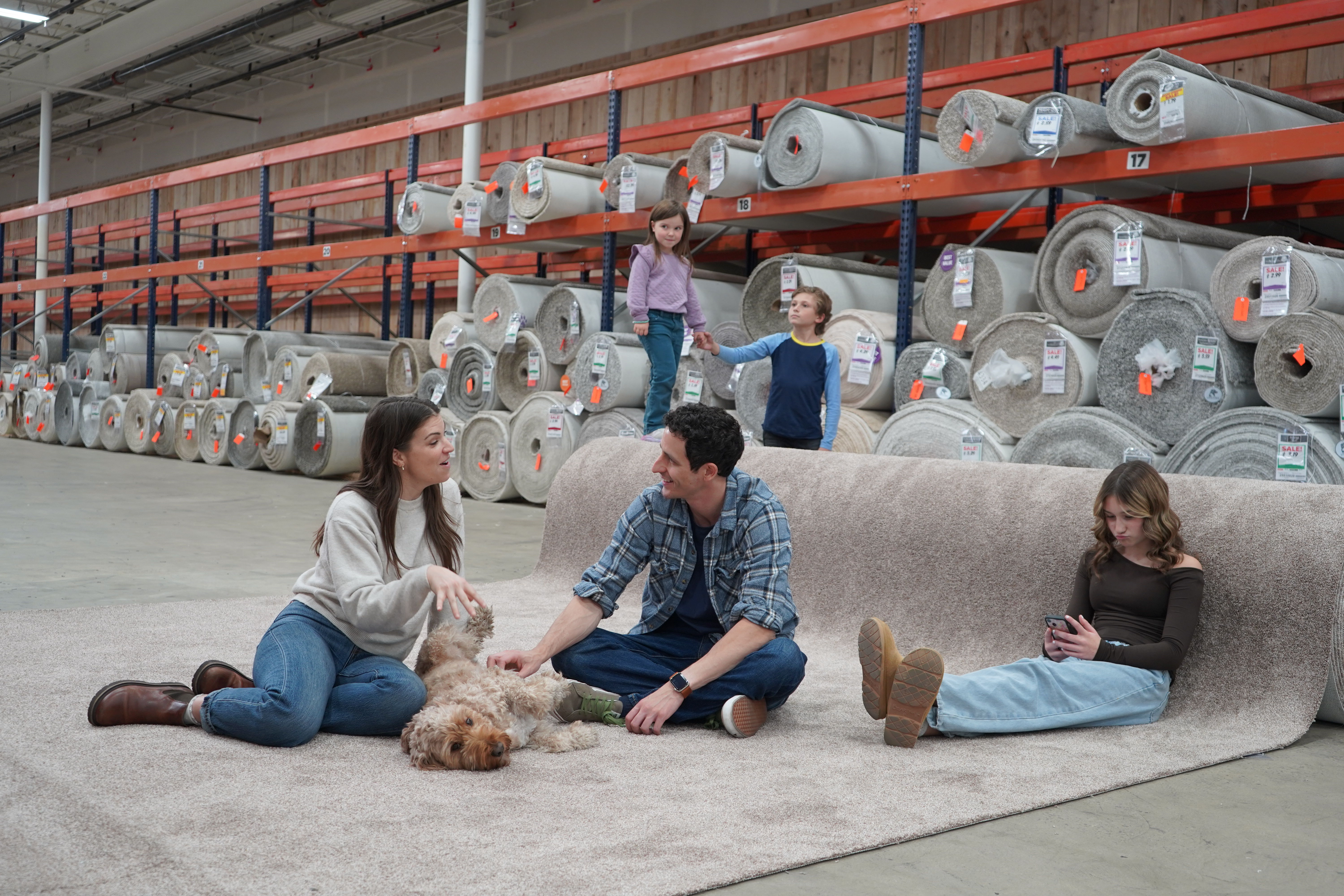 family sitting on carpet to test in flooring store