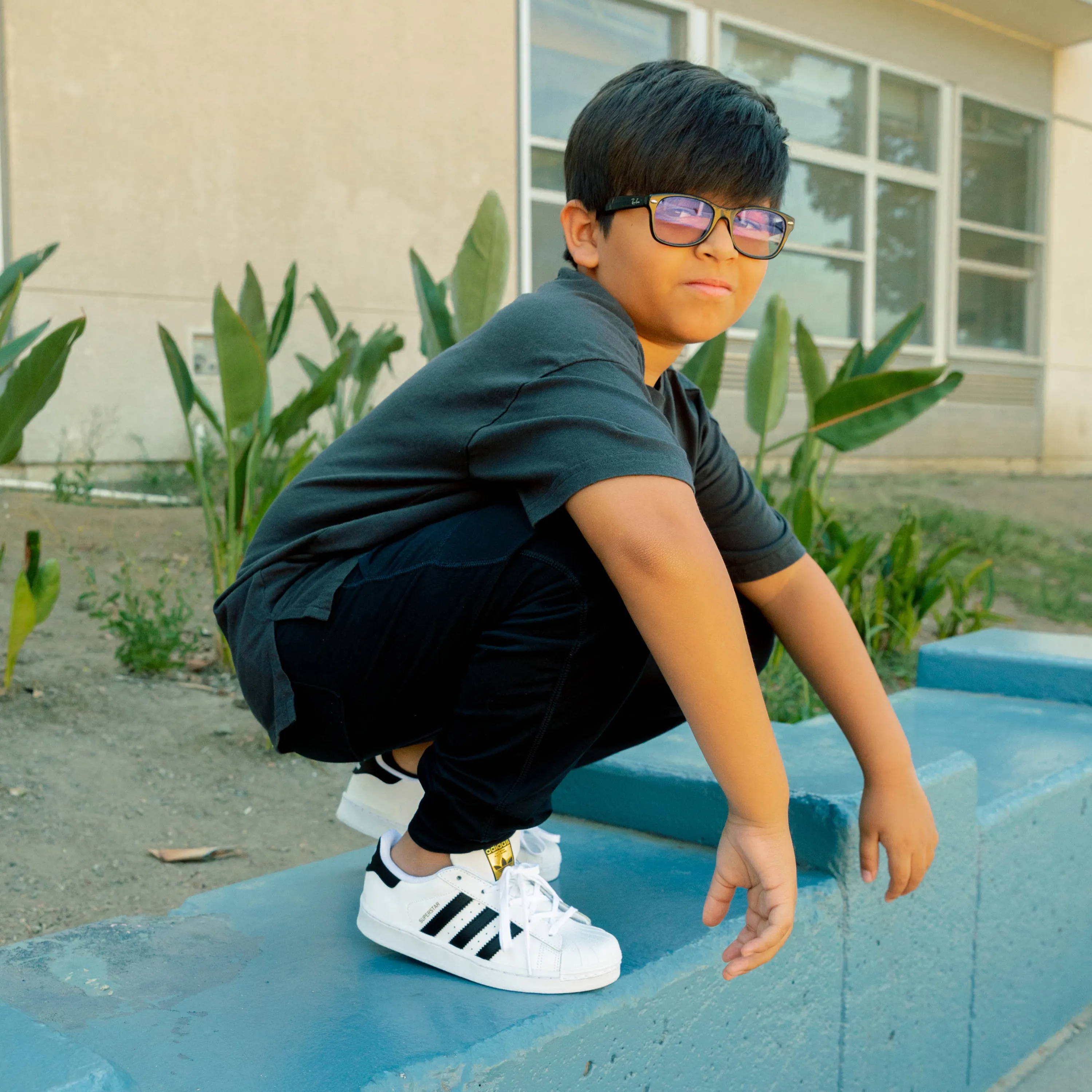 boy squatting at school waering adidas superstars