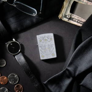 Lifestyle image of Painted Floral Satin Chrome Windproof Lighter laying with items such as money, a watch, ties, glasses, and coins.
