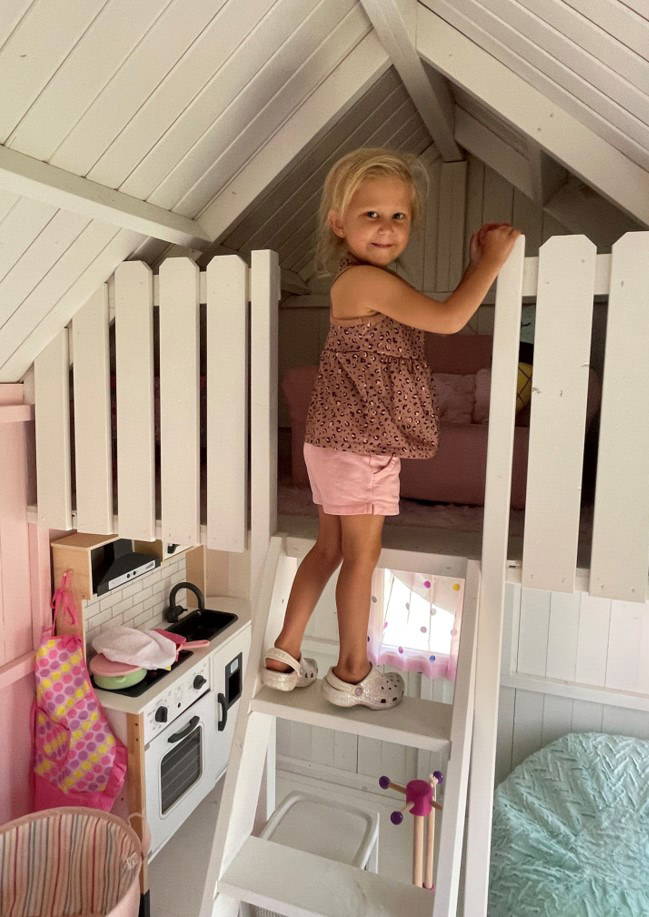 One girl goes up to the loft in the Farmhouse Style Playhouse by WholeWoodPlayhouses