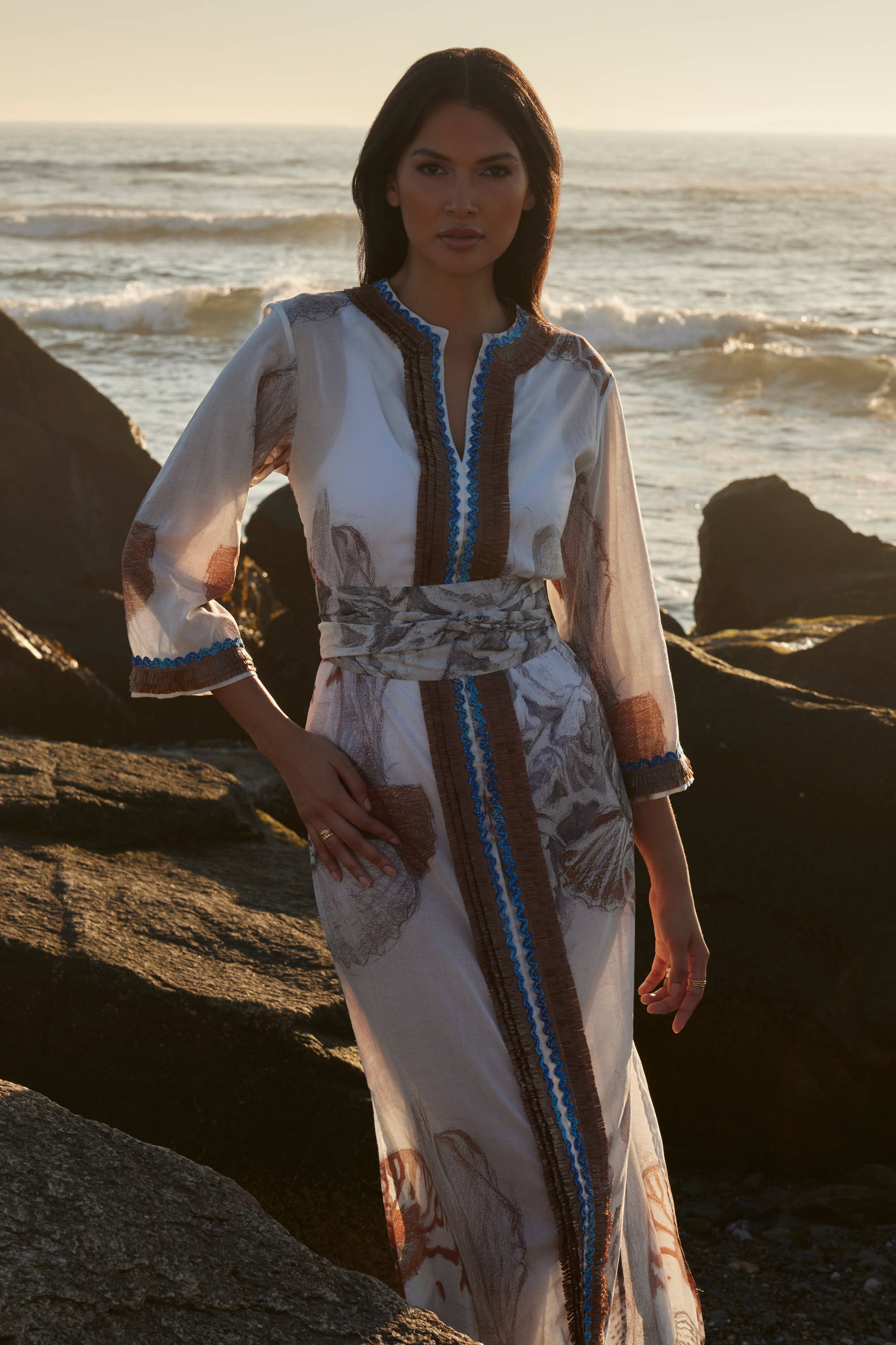 Woman wearing cotton kaftan with matching belt by the ocean by Ala von Auersperg