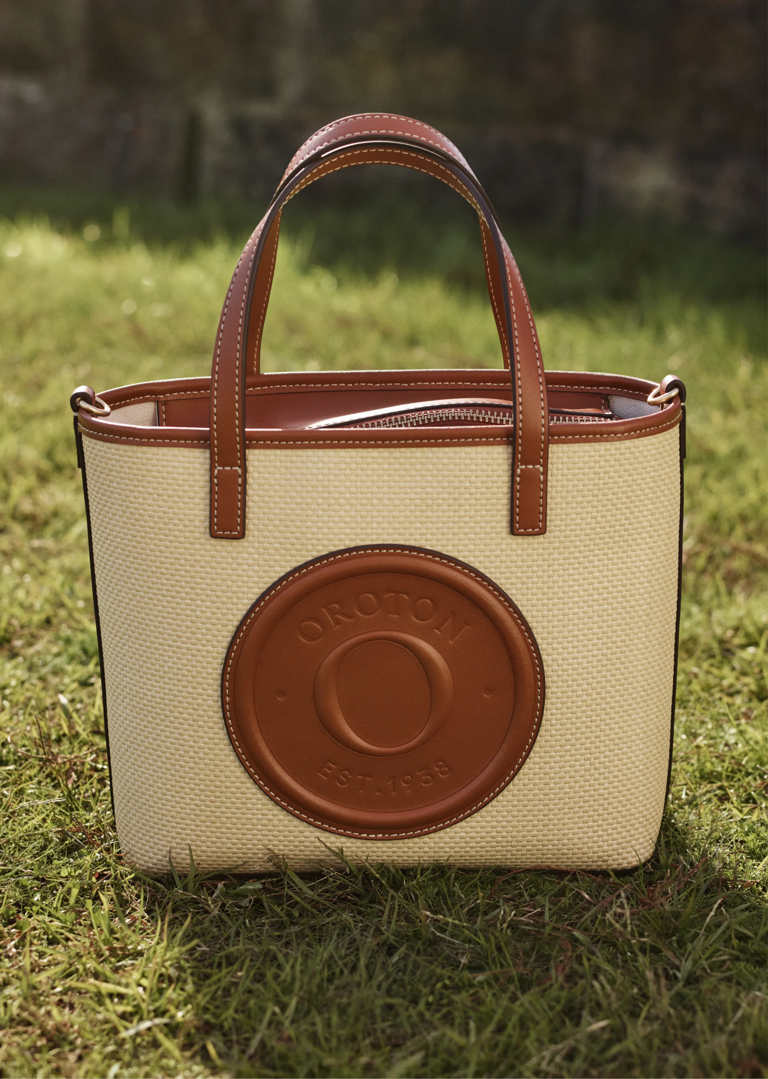 A beige tote bag with a brown logo on the front.