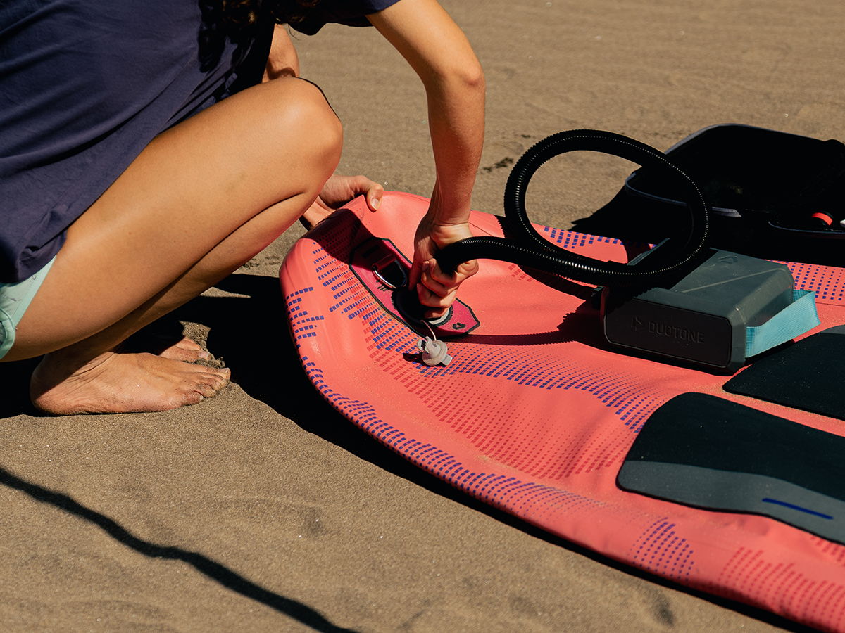 Person inflating a paddleboard on the beach.