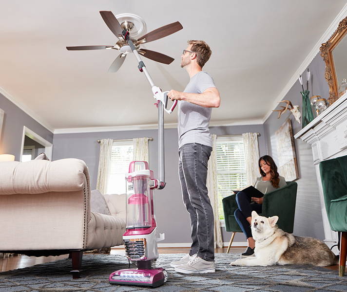 Man using Kenmore® vacuum to clean ceiling fan