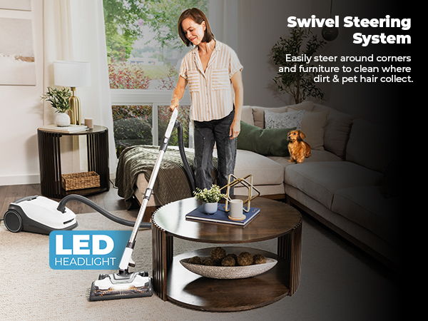 Woman vacuuming a living room with swivel steering and LED headlight features.
