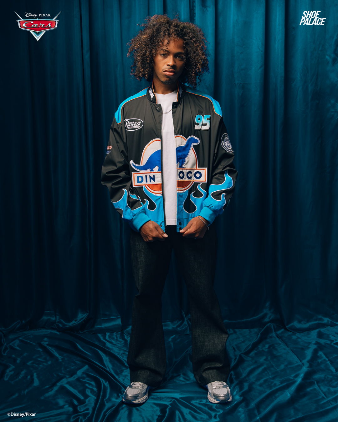 Person wearing a black and blue jacket stands against a blue backdrop.