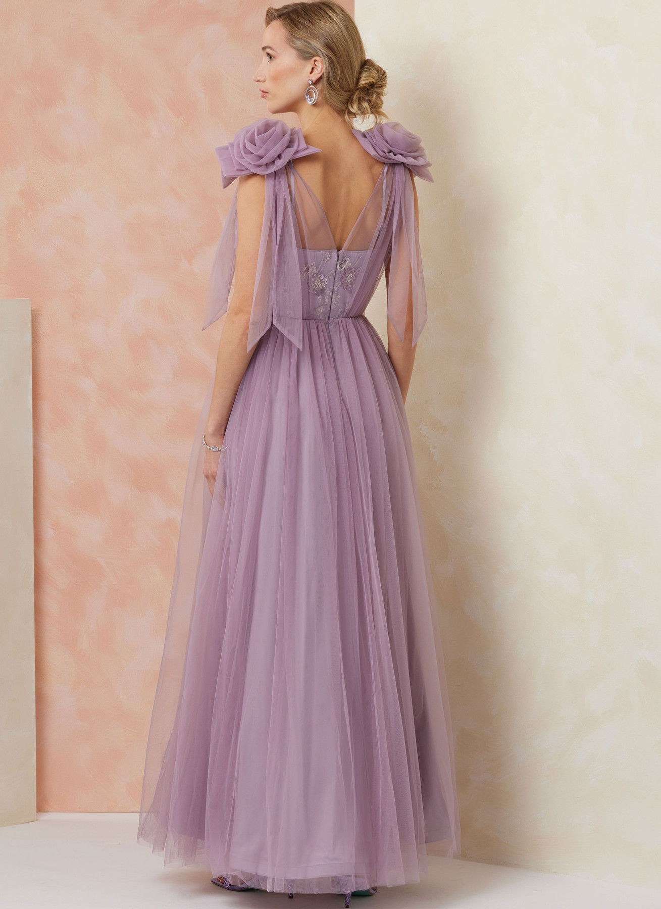 Woman wearing a lavender tulle gown with puff sleeves, viewed from the back.