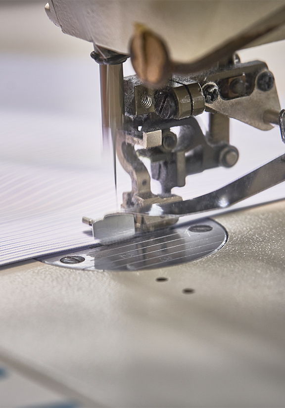 Close-up of a sewing machine needle stitching fabric.