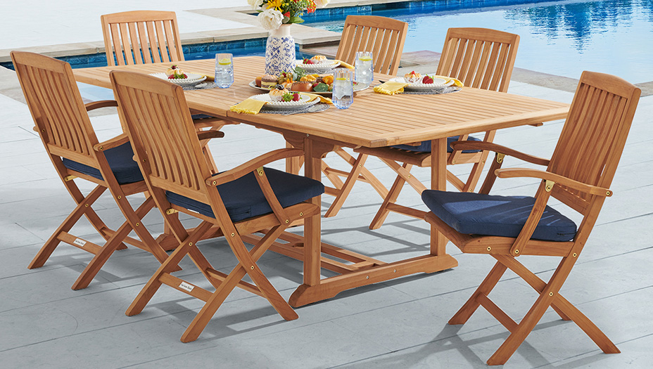 Wooden dining set with six chairs by a poolside.