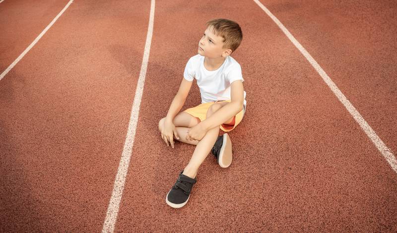 Boy sitting in the middle of the running track – exercise can trigger asthma so maybe he’s had to stop or can’t join in
