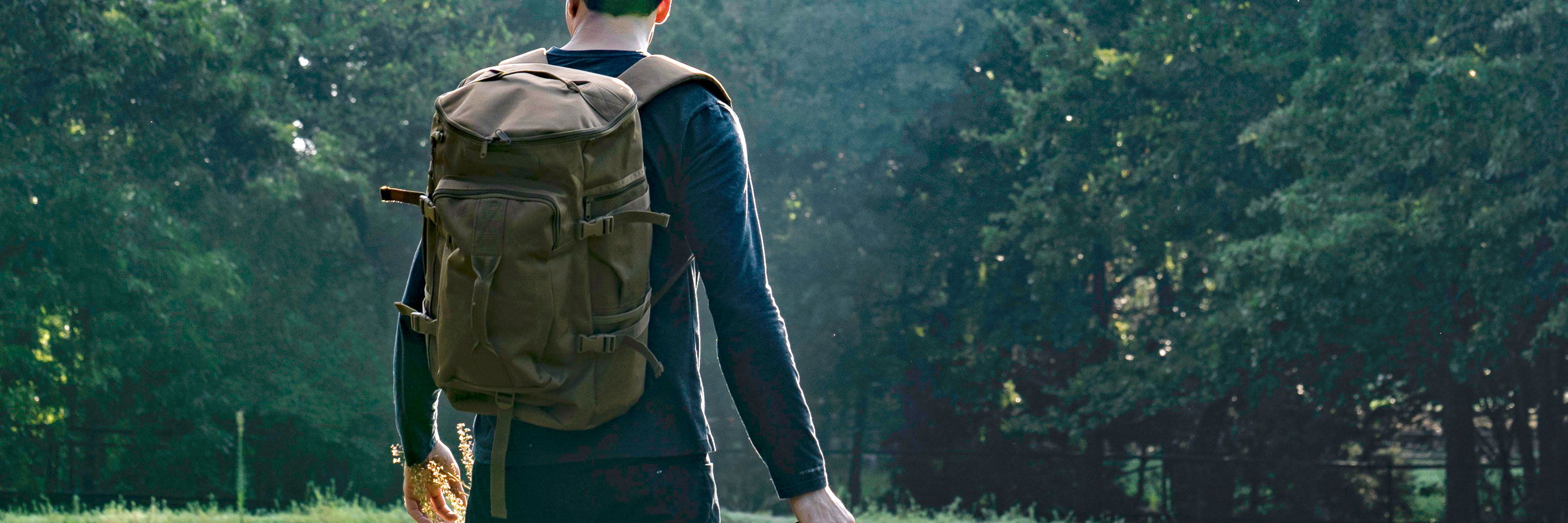 Man wearing Coyote Brown Top Load Duffel Backpack in woods.