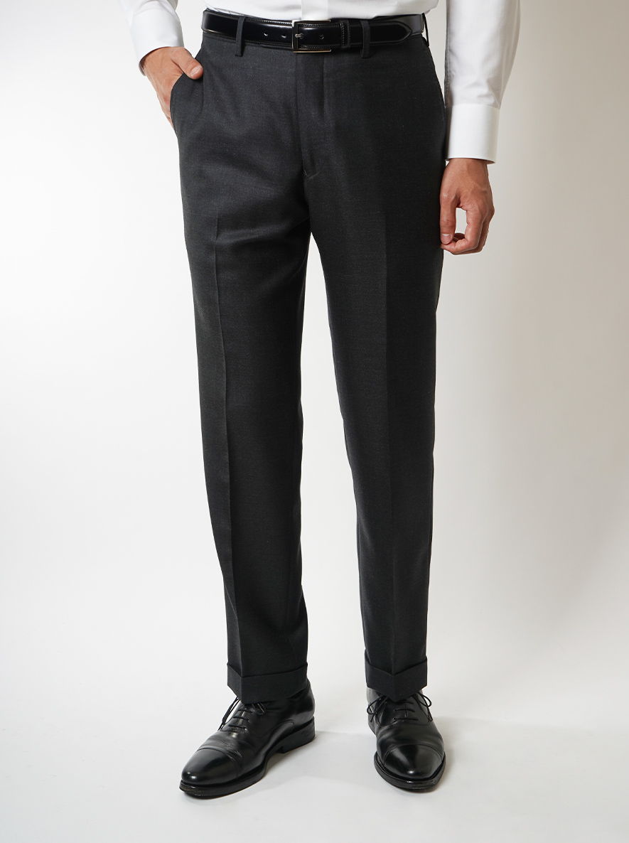 Man wearing black dress pants and shoes, standing against a white background.